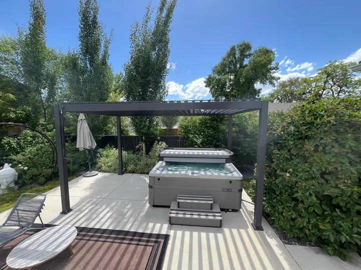 New hot tub installed on a concrete pad under a louvered pergola in a Salt Lake Valley backyard